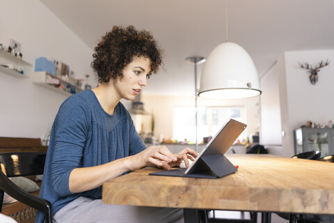 Young woman sitting at table, using digital tablet stock photo