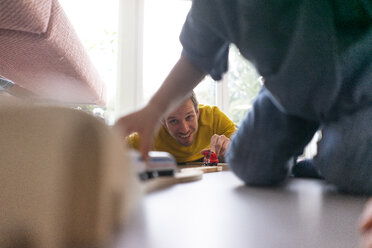 Vater und Sohn spielen zu Hause mit einer Spielzeugeisenbahn - JOSF03101