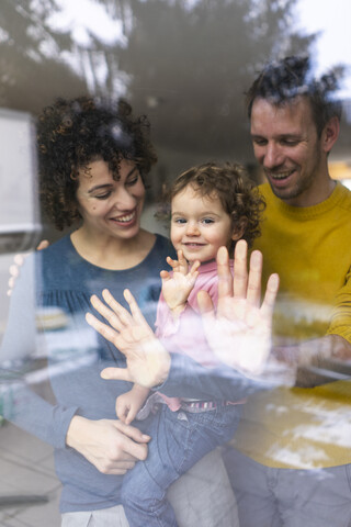 Familie schaut aus dem Fenster, Mutter trägt Tochter, berührt Glasscheibe, lizenzfreies Stockfoto