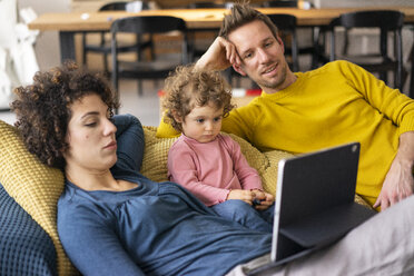 Family lying on couch watching movie on theit tablet - JOSF03108