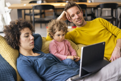 Familie liegt auf der Couch und schaut einen Film auf ihrem Tablet - JOSF03108