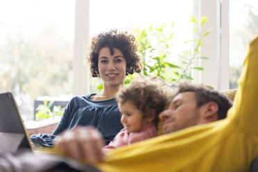 Familie liegt auf der Couch und schaut einen Film auf ihrem Tablet - JOSF03111