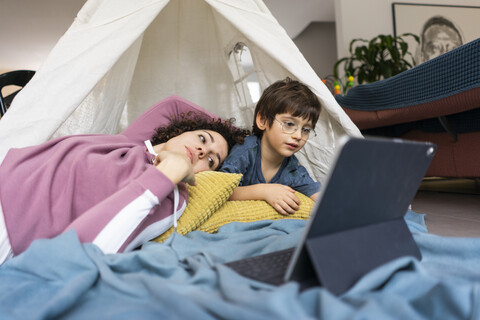 Mother and son lying in play tent, watching movie on tablet stock photo