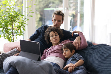 Familie liegt auf der Couch und schaut einen Film auf ihrem Tablet - JOSF03133