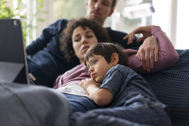 Familie liegt auf der Couch und schaut einen Film auf ihrem Tablet - JOSF03134