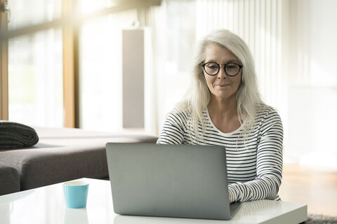 Portrait of mature woman using laptop at home stock photo