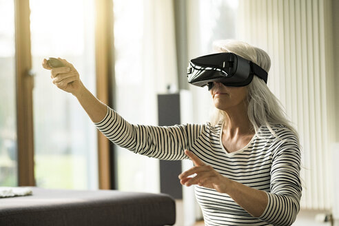 Eine Frau benutzt eine Virtual-Reality-Brille zu Hause - SBOF01884