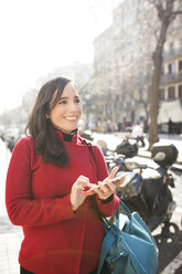 Lächelnde Frau mit Mobiltelefon in der Stadt - VABF02224