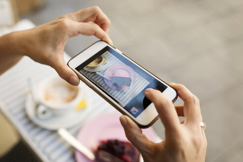 Weibliche Hände, die ein Bild von einem Stück Kuchen mit einem Smartphone machen - VABF02229