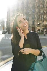 Elegante Frau, die in der Stadt mit einem Handy telefoniert - VABF02244