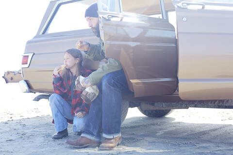 Tochter und Vater bei der Mittagspause am Strand in einem Auto, lizenzfreies Stockfoto