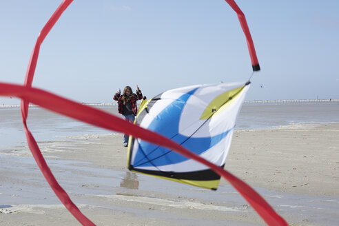 Germany, St Peter-Ording, girl flying kite on the beach - AMEF00034