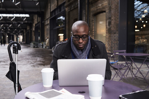 Porträt eines Geschäftsmannes, der im Coworking Space an einem Laptop arbeitet, lizenzfreies Stockfoto