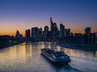 Deutschland, Hessen, Frankfurt, Skyline des Finanzviertels, Main und Deutschherrnbrücke, Frachtschiff bei Sonnenuntergang - AMF06803