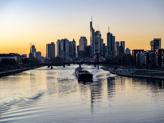 Deutschland, Hessen, Frankfurt, Skyline des Finanzviertels, Main und Deutschherrnbrücke, Frachtschiff bei Sonnenuntergang - AMF06805