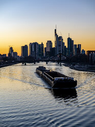 Deutschland, Hessen, Frankfurt, Skyline des Finanzviertels, Main und Deutschherrnbrücke, Frachtschiff bei Sonnenuntergang - AMF06811