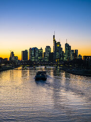 Deutschland, Hessen, Frankfurt, Skyline des Finanzviertels, Main und Deutschherrnbrücke, Frachtschiff bei Sonnenuntergang - AMF06812