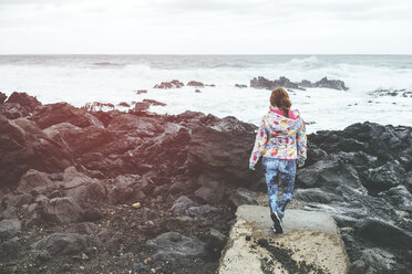 Portugal, Azoren-Inseln, Sao Miguel, Frau schaut von einer Felsenlandschaft auf das Meer - KIJF02412