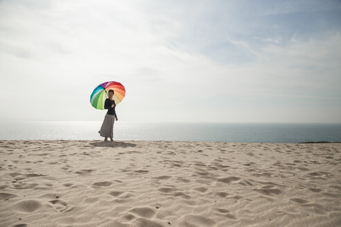 Frau mit buntem Regenschirm spazieren am Strand - KBF00549