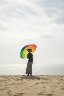Frau mit buntem Regenschirm am Strand stehend - KBF00551