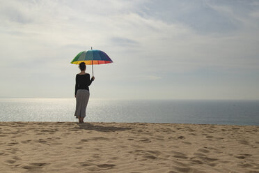 Frau mit buntem Regenschirm am Strand stehend, Rückansicht - KBF00552
