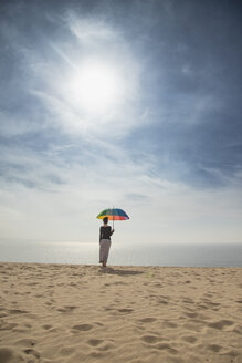 Frau mit buntem Regenschirm am Strand stehend, Rückansicht - KBF00553