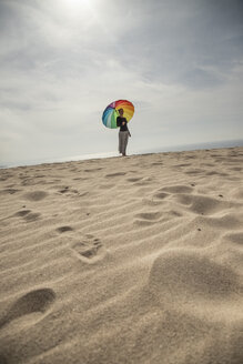 Frau mit buntem Regenschirm am Strand stehend - KBF00554