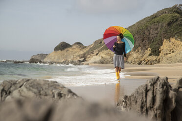Woman with colorful umbrella walking on the beach - KBF00559