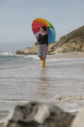 Woman with colorful umbrella standing on the beach - KBF00561