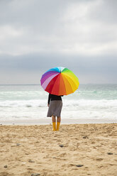 Frau mit buntem Regenschirm sitzt am Strand - KBF00566