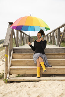 Frau mit buntem Regenschirm am Strand stehend - KBF00567