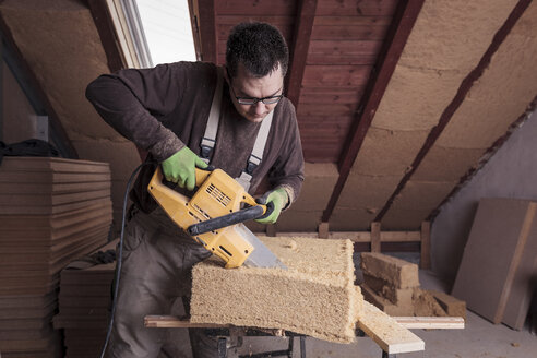 Dachisolierung, Arbeiter schneiden Holzfaserisolierung - SEBF00023