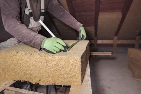 Roof insulation, worker measuring wood fibre insulation - SEBF00034