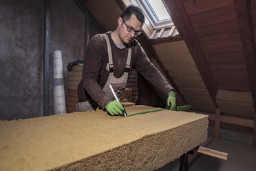 Roof insulation, worker measuring wood fibre insulation - SEBF00035