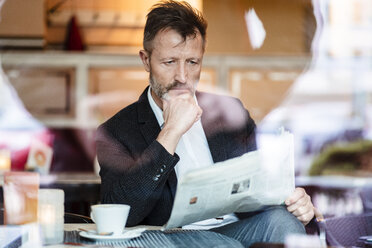 Portrait of pensive mature businessman reading newspaper in a coffee shop - DIGF06001