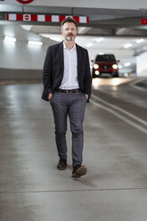 Portrait of mature businessman walking at underground car park - DIGF06028