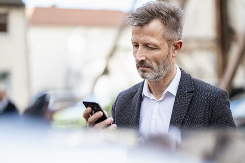 Portrait of mature businessman looking at cell phone stock photo