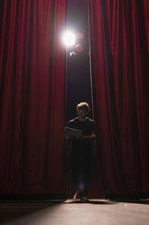 Barefoot actor walking on stage of theatre studying script - FBAF00264