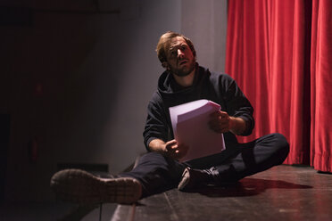 Schauspieler auf der Theaterbühne mit Skript sitzend - FBAF00269
