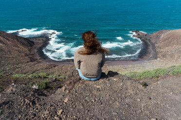 Spanien, Kanarische Inseln, Fuerteventura, Frau sitzt an der Küste - AFVF02563
