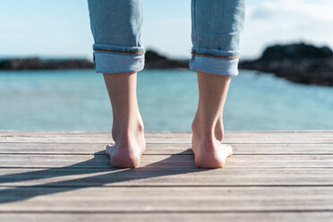 Spain, Canaray Islands, Fuerteventura, legs of a woman standing on jetty at the sea - AFVF02565