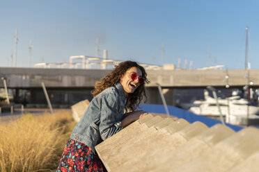 Portrait of laughing young woman leaning on a wall - AFVF02573