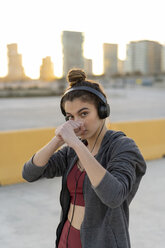 Sportliche junge Frau mit Kopfhörern beim Training, Boxen - AFVF02599