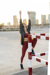 Sportive young woman with headphones during workout, raised arms - AFVF02604