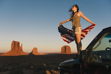 USA, Utah, Monument Valley, Frau mit Flagge der Vereinigten Staaten von Amerika genießt den Sonnenuntergang im Monument Valley - GEMF02868