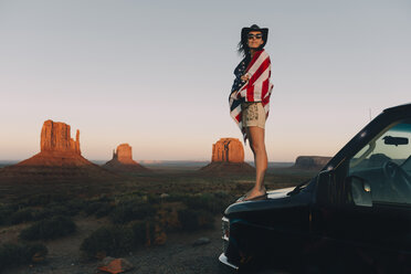 USA, Utah, Monument Valley, Frau mit Flagge der Vereinigten Staaten von Amerika genießt den Sonnenuntergang im Monument Valley - GEMF02870