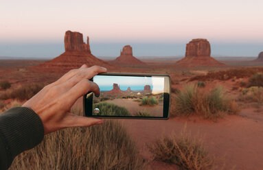 USA, Utah, Monument Valley bei Sonnenuntergang, Frauenhand beim Fotografieren mit Handy - GEMF02873