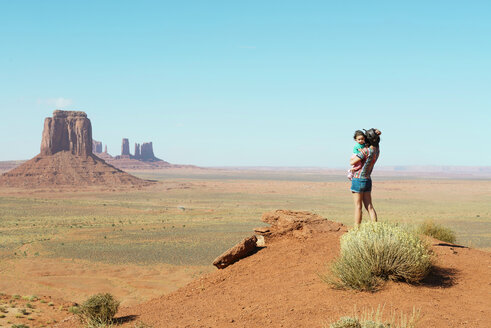USA, Utah, Monument Valley, Mutter reist mit Baby, Mutter trägt Mädchen, stehend auf Aussichtspunkt - GEMF02878
