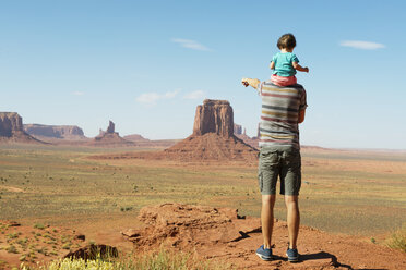 USA, Utah, Monument Valley, Vater reist mit Baby, Mädchen auf den Schultern und zeigt auf die Landschaft des Monument Valley - GEMF02879