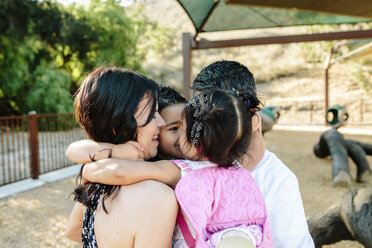 Glückliche Eltern, die ihre Kinder umarmen, während sie im Park stehen - CAVF62725